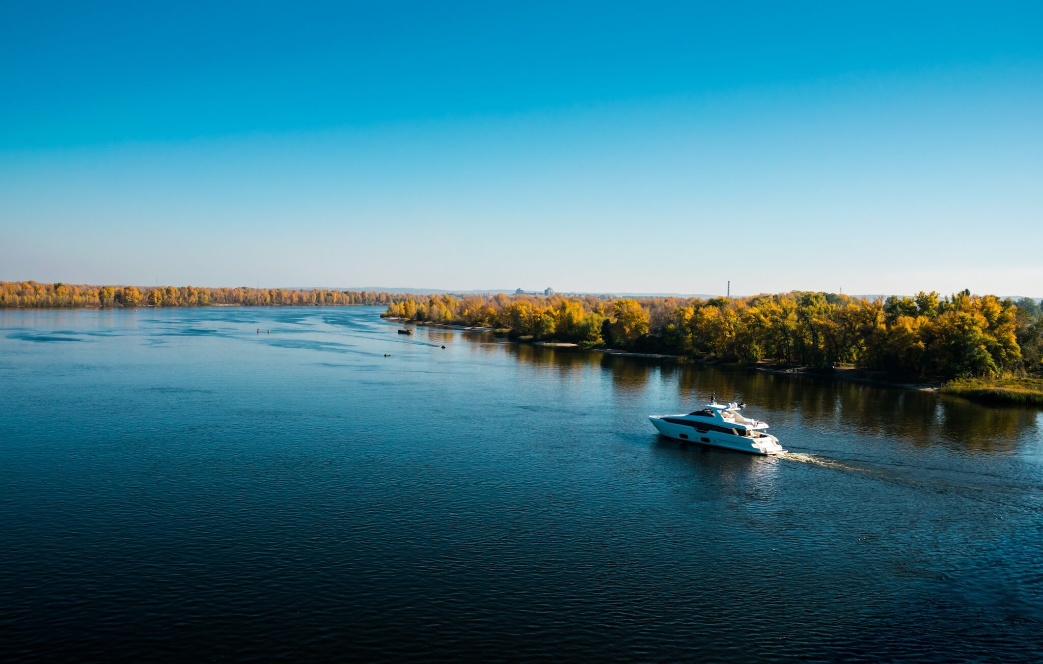 A motorboat traveling through a lake in early autumn.